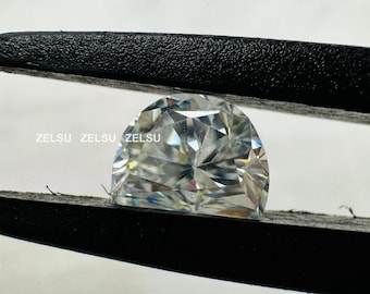 May include: A clear, faceted, cushion-shaped gemstone held in a black, textured tweezer. The gemstone is reflecting light and has a rainbow effect.