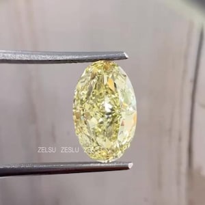 May include: A yellow oval-shaped gemstone held by tweezers. The gemstone is faceted and has a bright, clear colour.