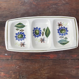 May include: A rustic wooden sign with the text "Welcome" in a handwritten style. The sign is painted white with a distressed finish, and features a decorative floral element in the corner. The background is a blurred image of a wooden surface.