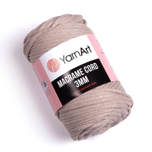 May include: A roll of beige macrame cord with a pink and black label that reads 'YarnArt Macrame Cord 3MM www.yarnart.info'