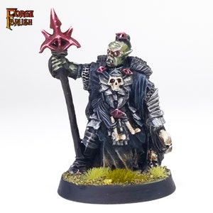 May include: A green-skinned Orc miniature figure wearing black armor and a dark robe, holding a red-tipped spear. The figure has a skull on its chest and is adorned with red gems. The figure is standing on a black base with green grass.