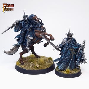 Könnte beinhalten: Zwei bemalte Miniaturfiguren des Herr der Ringe-Charakters, der Hexenkönig von Angmar, eine zu Pferd und eine zu Fuß. Beide Figuren tragen schwarze Roben mit silberner Rüstung und eine Krone mit Stacheln. Die Figuren sind in Kampfstellung.