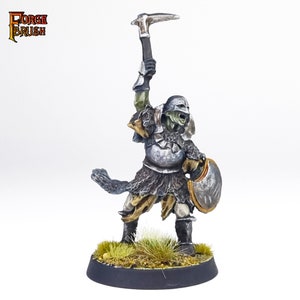 May include: A green-skinned Orc warrior miniature figure wearing chainmail armour and holding a pickaxe and shield. The figure is painted in silver, brown, and gold.