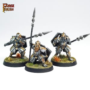 May include: Three miniature figures of dwarves wearing silver and gold armor, holding spears and shields. The figures are painted in a realistic style and are standing on black bases.
