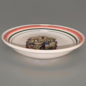 May include: White ceramic pasta bowl with a red and green striped rim. The bowl features a central illustration with the word "Pasta" and a depiction of a person harvesting wheat. A classic design for serving pasta dishes.