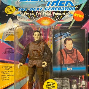 May include: A Star Trek: The Next Generation action figure of Lore, Data's evil brother, wearing a brown and black outfit. The figure includes a Starfleet action base and a collector card. The packaging features the Star Trek logo and the words "Space. The Final Frontier."