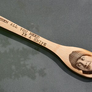Puede incluir: Una cuchara de madera con el texto "When all you need is a knife" grabado en ella. Tambi&eacute;n hay un rostro de una persona grabado en la cuchara.
