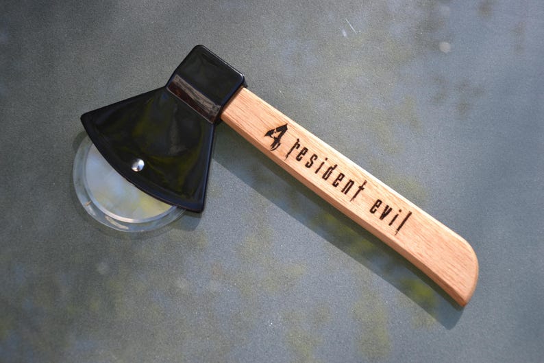 May include: A black pizza cutter shaped like an axe with a wooden handle. The handle is engraved with "4 resident evil".