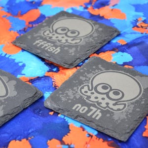 Puede incluir: Tres posavasos de pizarra gris con un diseño de pulpo en blanco y negro. Los posavasos tienen las palabras "fffish", "no 7h" y "no 7h" impresas en ellos.