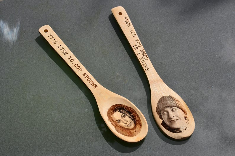 Puede incluir: Dos cucharas de madera con refranes grabados. Una cuchara dice "Cuando todo lo que necesitas es un cuchillo" y la otra dice "Es como 10.000 cucharas".