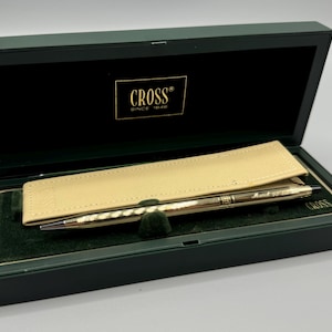 May include: A gold pen with a black and gold Cross pen case. The pen is in a green box with the Cross logo and the words "Since 1846".