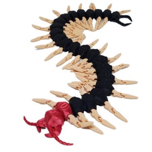 May include: An articulated centipede toy featuring a metallic red head with two antennae, followed by a segmented body alternating between matte black and beige sections. Each segment includes two beige pointed legs extending outward.