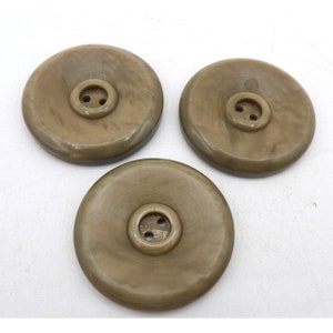 May include: Three brown plastic buttons with two holes each. The buttons are round and have a raised center.