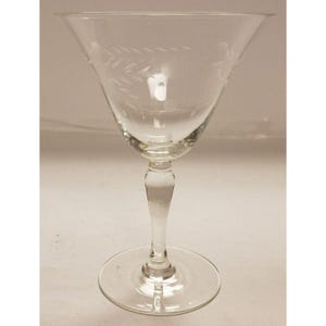 Peut inclure: Un verre à cocktail en verre transparent à pied avec un motif gravé. Le verre a un bol large et une longue tige fine.