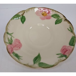 May include: A white ceramic saucer with a scalloped edge features a floral design with pink roses and green leaves.