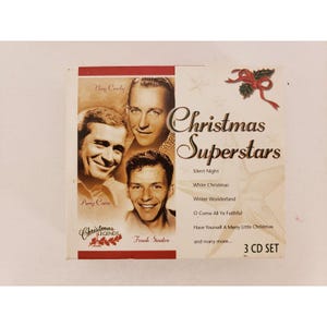 Puede incluir: Un set de 3 CD de Christmas Superstars con Bing Crosby, Perry Como y Frank Sinatra. La portada del álbum tiene un fondo blanco con el título en escritura elegante y un diseño de acebo y cinta.