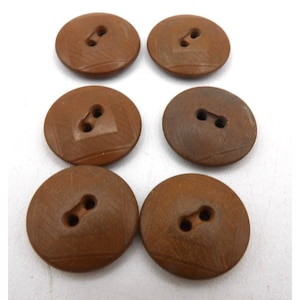 May include: Six brown ceramic buttons with two holes each. The buttons have a square pattern etched into the surface.