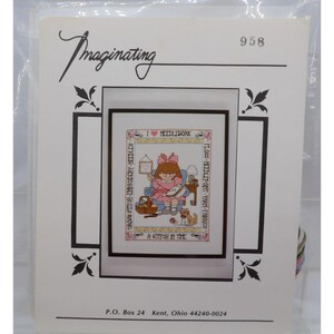 May include: Cross stitch pattern featuring a girl sitting in a chair with a needle and thread, surrounded by embroidery supplies. The pattern includes the text "I ♥ NEEDLEWORK" and "A Stitch in Time".