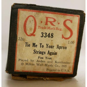 Puede incluir: Una caja de música QRS vintage con una etiqueta en blanco y negro. La etiqueta dice "Tie Me To Your Apron Strings Again" y "Fox Trot". La caja de música está numerada 3348 y 226.