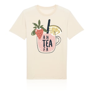 Peut inclure: Un t-shirt à manches courtes de couleur crème avec un motif représentant une boisson rose dans une tasse en verre. Le dessin inclut une fraise, une tranche de citron et une paille noire, avec le texte AN TEA FA imprimé en noir sur la tasse.