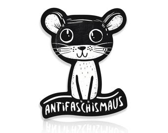 May include: A black and white cartoon mouse illustration with the text "ANTIFASCHISMA" on a curved banner. The mouse has large eyes, whiskers, and a smiling expression. The design is simple and graphic, with a clean, modern aesthetic.