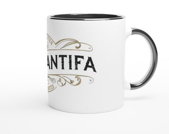 May include: White ceramic coffee mug with a black rim and handle. The mug features a black and gold graphic with the word "ANTIFA" in a vintage style font.