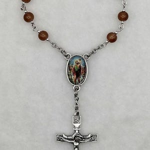 May include: A brown beaded rosary with a silver crucifix and a silver oval charm featuring a depiction of Saint Christopher carrying a child. The charm has the words "INRI" on it.
