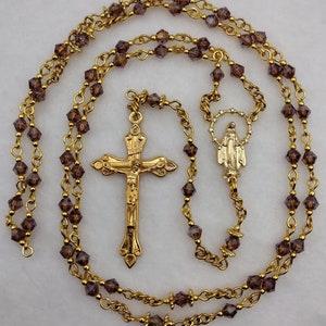 Rosario della Madonna Aurora viola in cristallo dorato con centrotavola con medaglia miracolosa traforata e crocifisso decorato a forma di lacrima