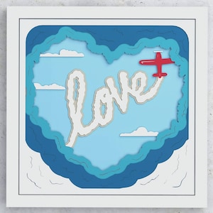 May include: A paper craft image of a red airplane flying through a blue sky, leaving a white trail in the shape of the word "LOVE".