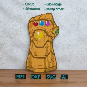 Pode incluir: Uma manopla dourada com seis pedras preciosas coloridas, inspirada em uma popular série de quadrinhos. A imagem inclui o texto "- Cricut - Silhouette - Glowforge - Many others" e abreviações de tipos de arquivo: EPS, DXF, SVG e AI.