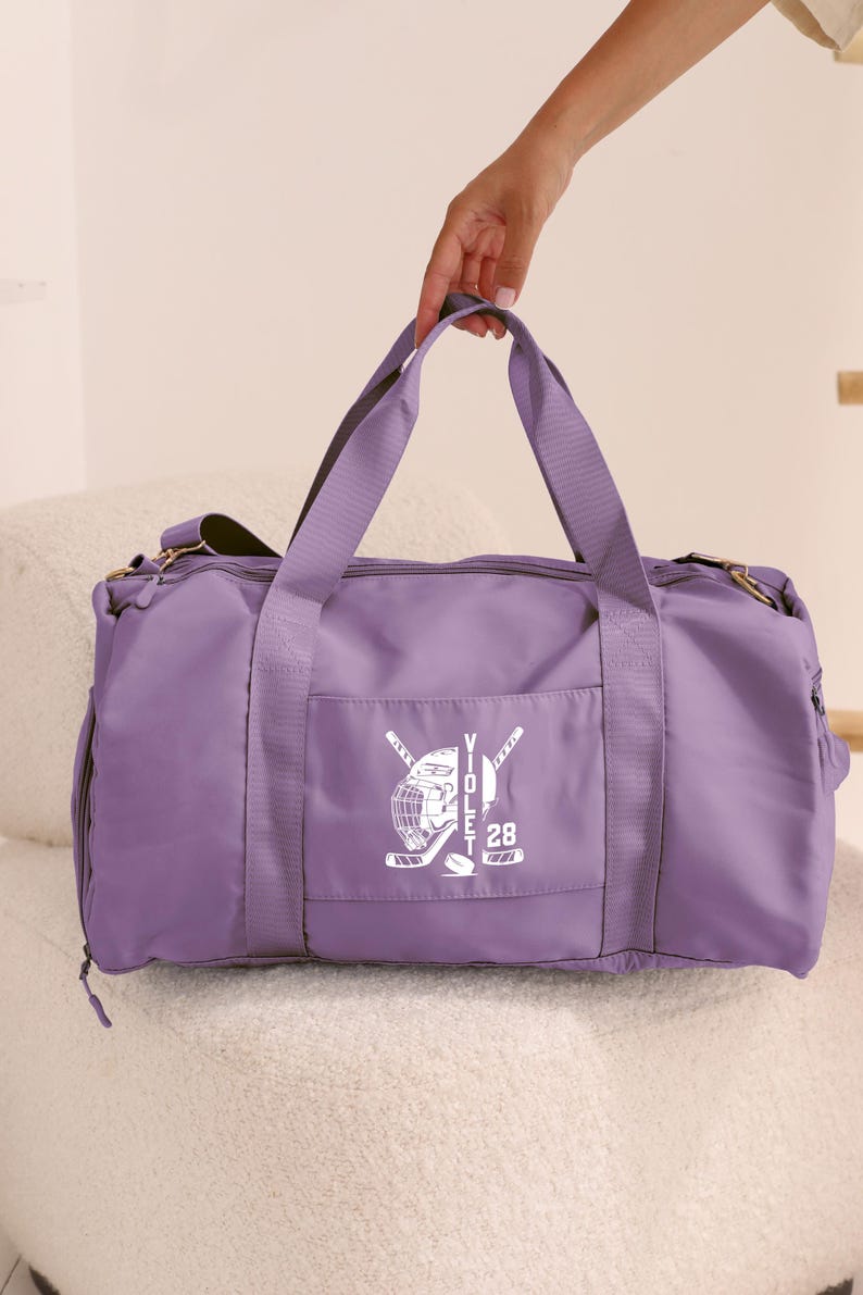 May include: Purple duffel bag with a white hockey helmet and stick graphic, the text "VIOLET 28" is printed on the bag.