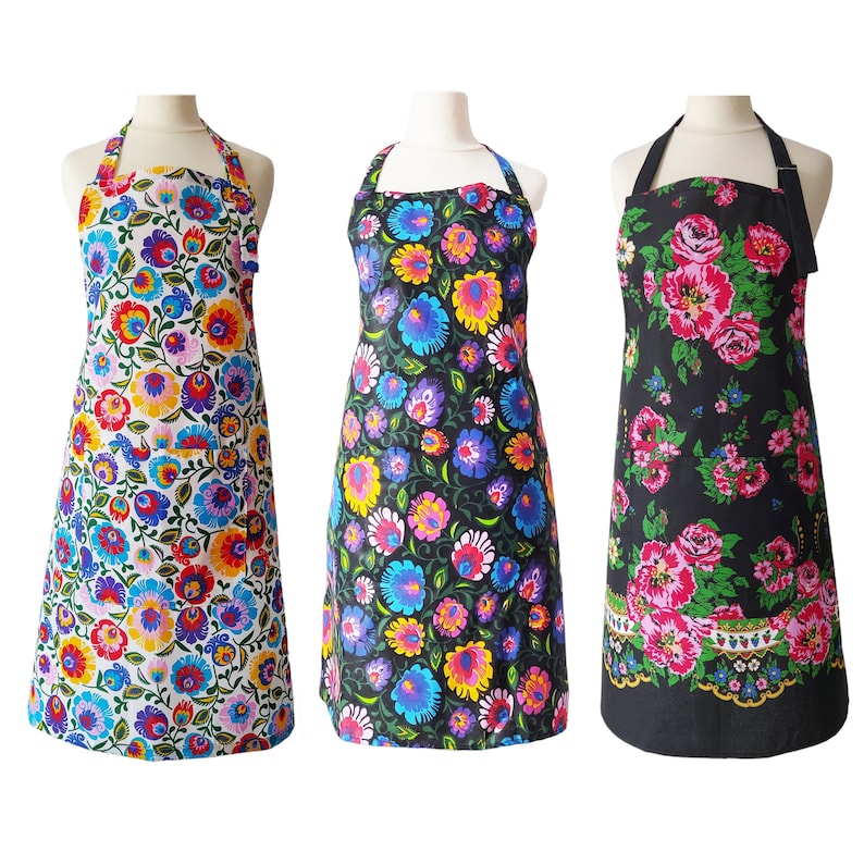 May include: Three floral print aprons with adjustable straps. The aprons are black with pink and white flowers, white with multi-colored flowers, and black with blue and yellow flowers.