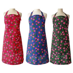 Könnte beinhalten: Drei Schürzen mit Blumenmuster. Die Schürzen sind rot, blau und schwarz mit einem rosafarbenen Blumendesign. Jede Schürze hat eine Tasche auf der Vorderseite.