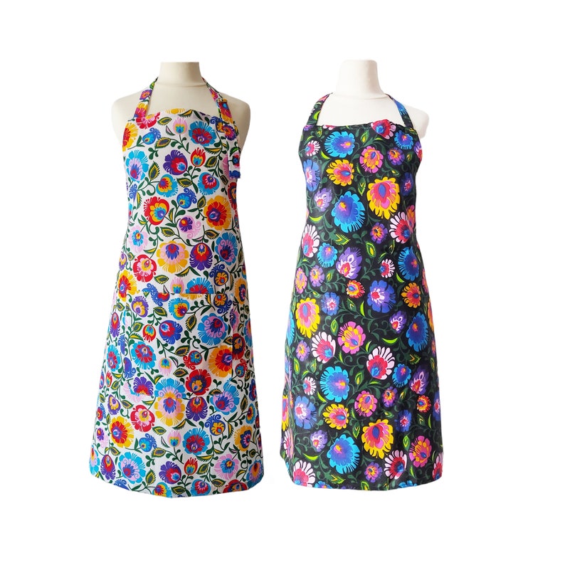 May include: Two floral print aprons, one with a white background and the other with a black background. Both aprons have a colorful floral pattern with red, blue, yellow, and green flowers.