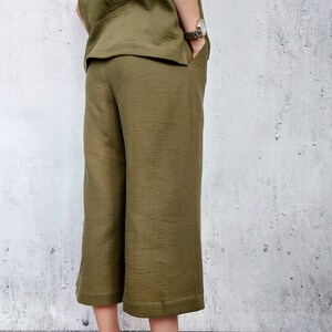 May include: Olive green culottes with a wide leg and a slightly cropped length. The pants have a smooth, textured fabric.