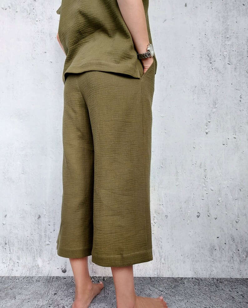 May include: Olive green culottes with a wide leg and a slightly cropped length. The pants have a smooth, textured fabric.