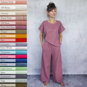 May include: A woman wearing a mauve-colored two-piece pajama set with a loose-fitting top and wide-leg pants. The fabric has a textured waffle weave.