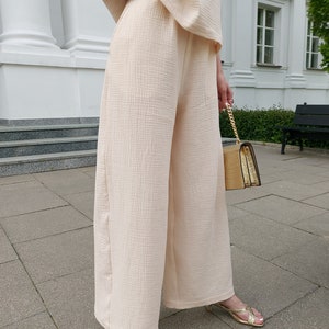May include: A pair of wide-leg pants in a light cream color. The pants are made of a soft, textured fabric and have a relaxed fit.