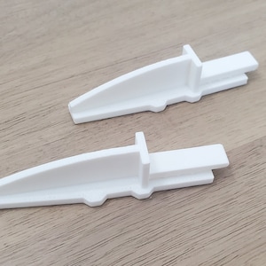 May include: Two white plastic corner guards with a curved design. The guards are designed to protect corners from damage.