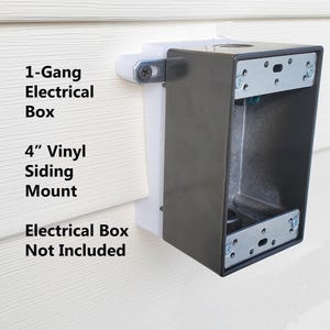 May include: A 1-gang electrical box mount for 4" vinyl siding. The mount is made of white plastic and has a black metal electrical box. The text "1-Gang Electrical Box" and "4" Vinyl Siding Mount" is printed on the white plastic. The text "Electrical Box Not Included" is printed below the mount.