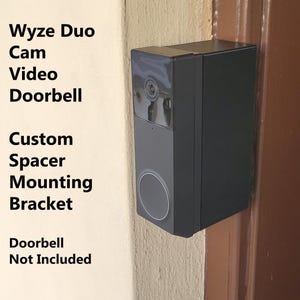 May include: A black custom spacer mounting bracket for a Wyze Duo Cam Video Doorbell. The text "Wyze Duo Cam Video Doorbell" and "Custom Spacer Mounting Bracket" is printed on the wall. The text "Doorbell Not Included" is also printed on the wall.