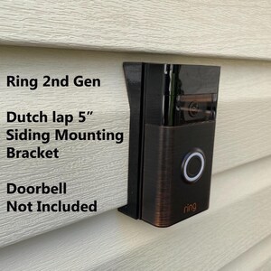 May include: A brown Ring 2nd Gen doorbell mounted on a white siding with a Dutch lap 5" siding mounting bracket. The text "Doorbell Not Included" is written below the doorbell.