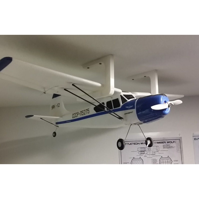 Op de afbeelding: Een wit en blauw modelvliegtuig met de tekst "CCCP-115275" aan de zijkant. Het vliegtuig hangt aan het plafond met een witte beugel.