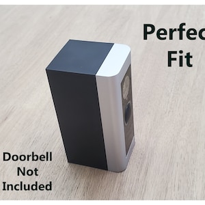 May include: A black and silver doorbell mount with the text "Perfect Fit" printed in black. The text "Doorbell Not Included" is printed in black below the mount.