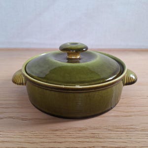 Op de afbeelding: Een groene keramische ovenschaal met een deksel. De schaal heeft een ronde vorm met twee handvatten en een knop op het deksel. De kleur is een diep, glanzend groen.