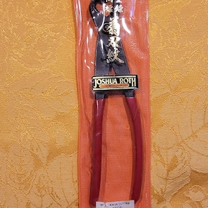 May include: A pair of red-handled knob cutters in a clear orange plastic sleeve. The black cutting blades have gold lettering and the brand name "JOSHUA ROTH" is visible. The package also includes Japanese text.