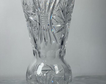 May include: A clear glass vase with a cut crystal design. The vase has a wide mouth and a narrow base.