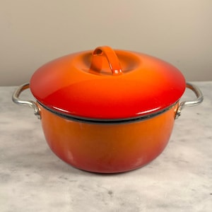 May include: Orange and red enamel cast iron pot with a lid and silver handles.