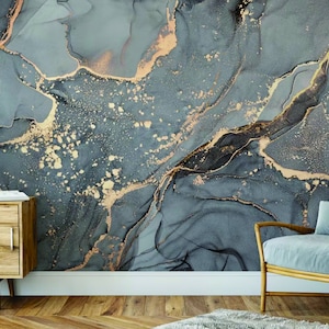 Puede incluir: Un papel tapiz abstracto de mármol gris y dorado con una lámpara azul claro y un sillón gris en primer plano.