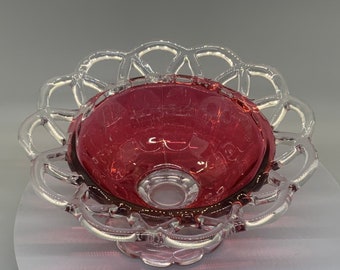 May include: A vintage glass bowl with a clear, lacy rim and a deep, ruby red interior. The bowl has a delicate, feminine design and would be perfect for serving desserts or candies.